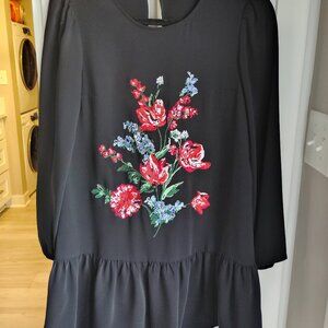 A feminine babydoll style dress made extra special with bright floral embroidery